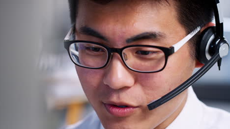 Young-Asian-man-working-in-a-call-centre,-close-up