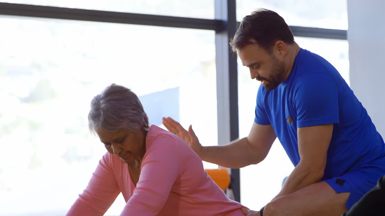entrenador ayudando a una mujer mayor en la realización de yoga 4k