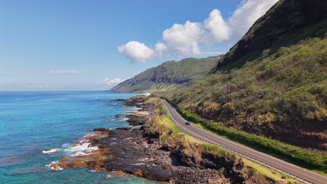 car driving on a coastal highway along a rocky shore in oahu, hawaii, aerial