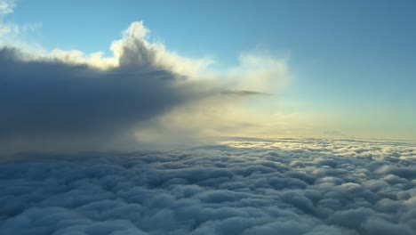 an aerial view taken from inside a jet cockpit flying over an endless sea of clouds, with a storm cloud on the left. scene illuminated by the warm sunrise light.