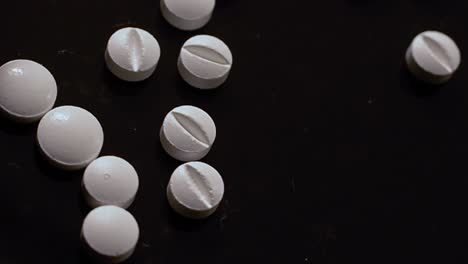 Drug-selection---white-tablets-selected-by-hand-with-gloved-hands-on-a-black-surface