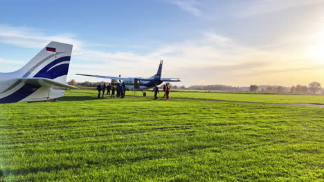 wide shot of a few parachuters getting ready and walking to the plane on the ground