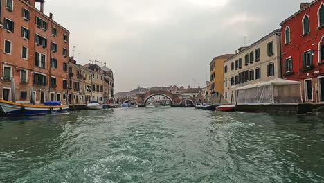 water surface pov of venice seen from sailing ferry boat with ponte dei tre archi bridge in background , venice in italy