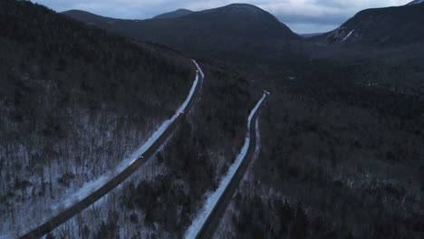 drone video at dusk in the mountains with cars driving toward the drone