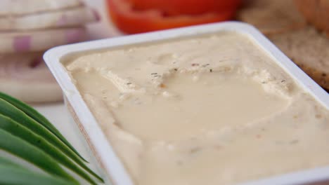 cream cheese in container with bread and vegetables