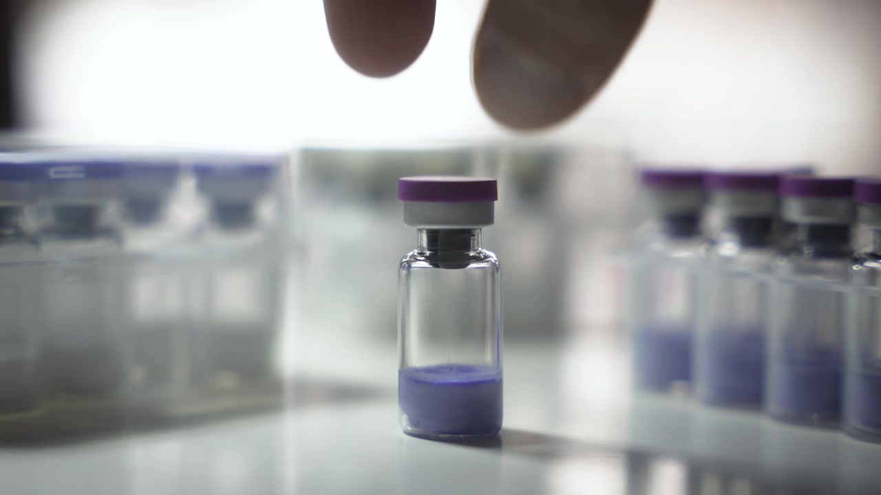 Una mano prende una fiala e la ripone sul tavolo, inquadratura statica [Peptide]
