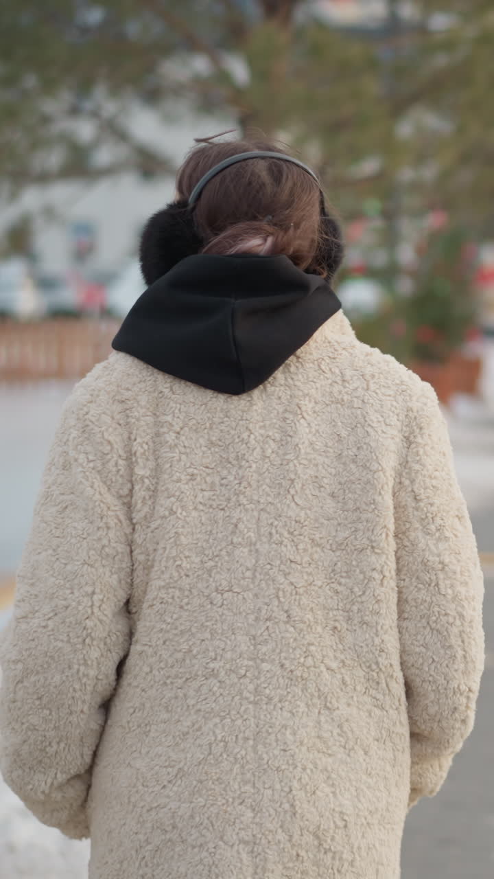 Joven con abrigo mirando hacia arriba, manos en los bolsillos con orejeras en una pausa contemplativa en una calle bordeada de pinos, luz invernal suave, aliento visible, ambiente curioso y sutil soledad urbana