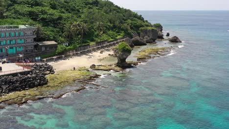 aerial drone footage of tranquil beach with famous flower vase rock as centerpiece and translucent turquoise sea water crashing the shore at xioliuqiu lambai island, pingtung county, taiwan