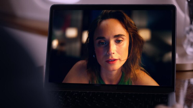Donna preoccupata che chatta sul web con il portatile, primo piano. Uomo che fa una videochiamata, ripreso dalla spalla