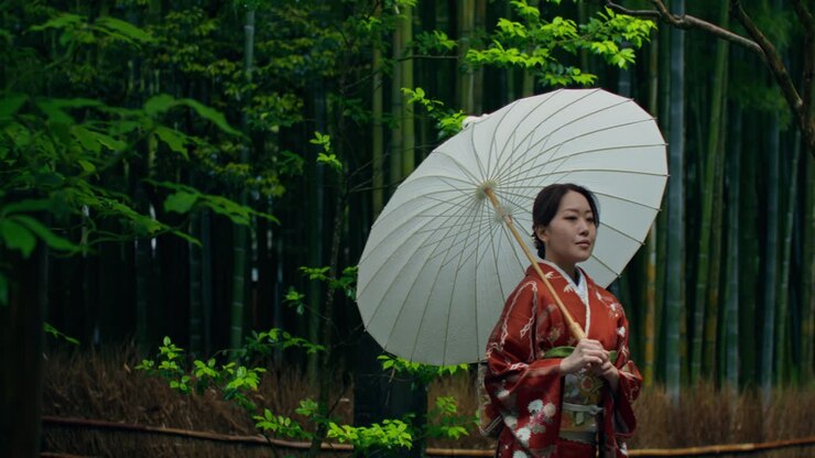 Donna in Kimono con ombrello in una foresta di bambù