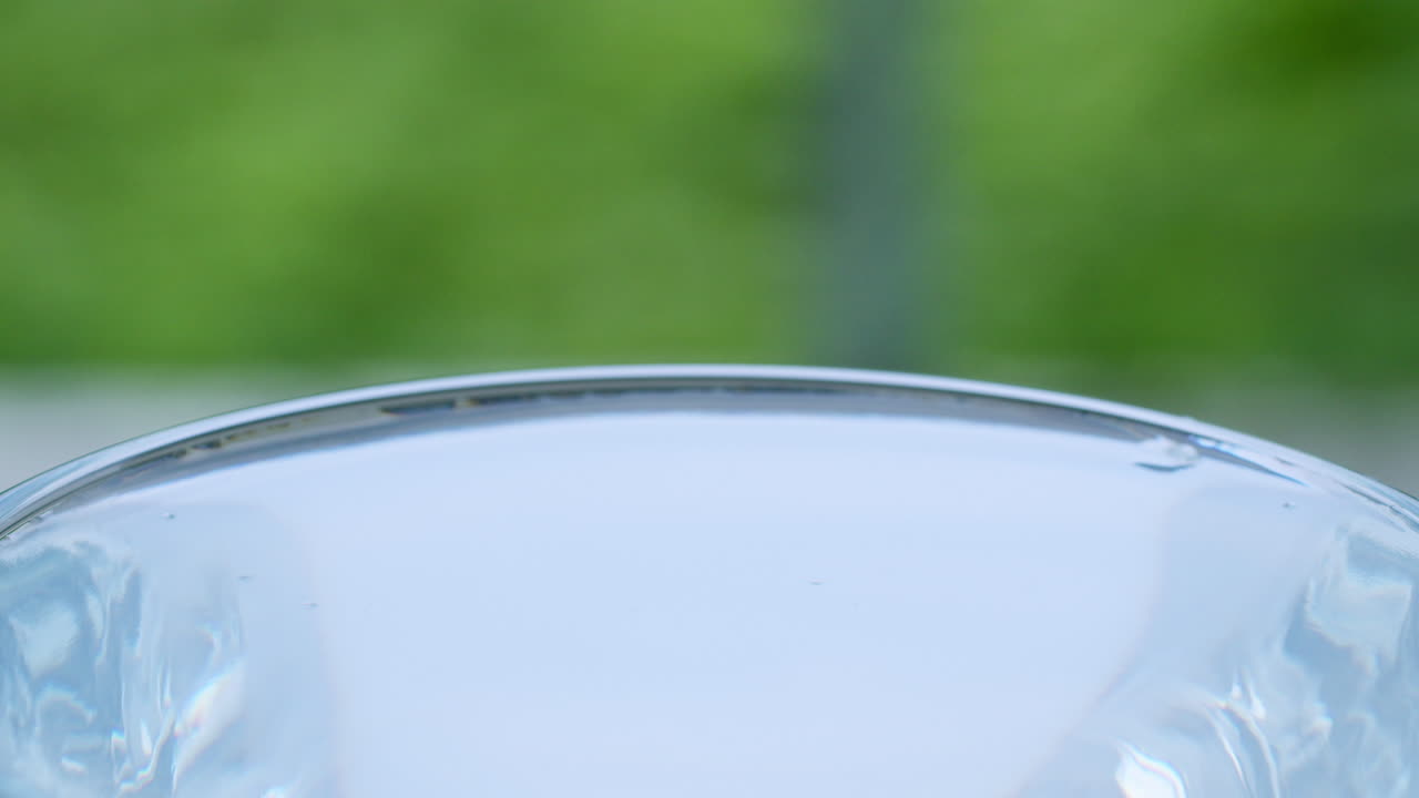 작은 물방울이 물로 가득 찬 잔에서 파동과 파동을 일으키는 클로즈업