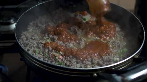 tomato sauce being added to sizzling mince meat