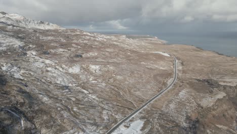 Aerial-shot-of-Old-Man-of-Storr-on-Isle-of-Skye,-Scotland-with-visible-road-and-coastline,-cloudy-skies