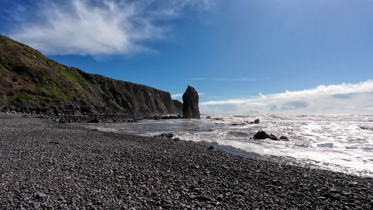 Seascapes sea stack shingle beach sea cliffs blue sky at Ballydwane beach in Waterford Ireland