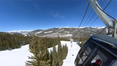 Snowy-mountains-viewed-from-outside-of-gondola-while-carrying-skiers-and-snowboarders-to-the-top-of-a-ski-run