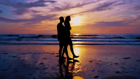 couple walking on beach at sunset