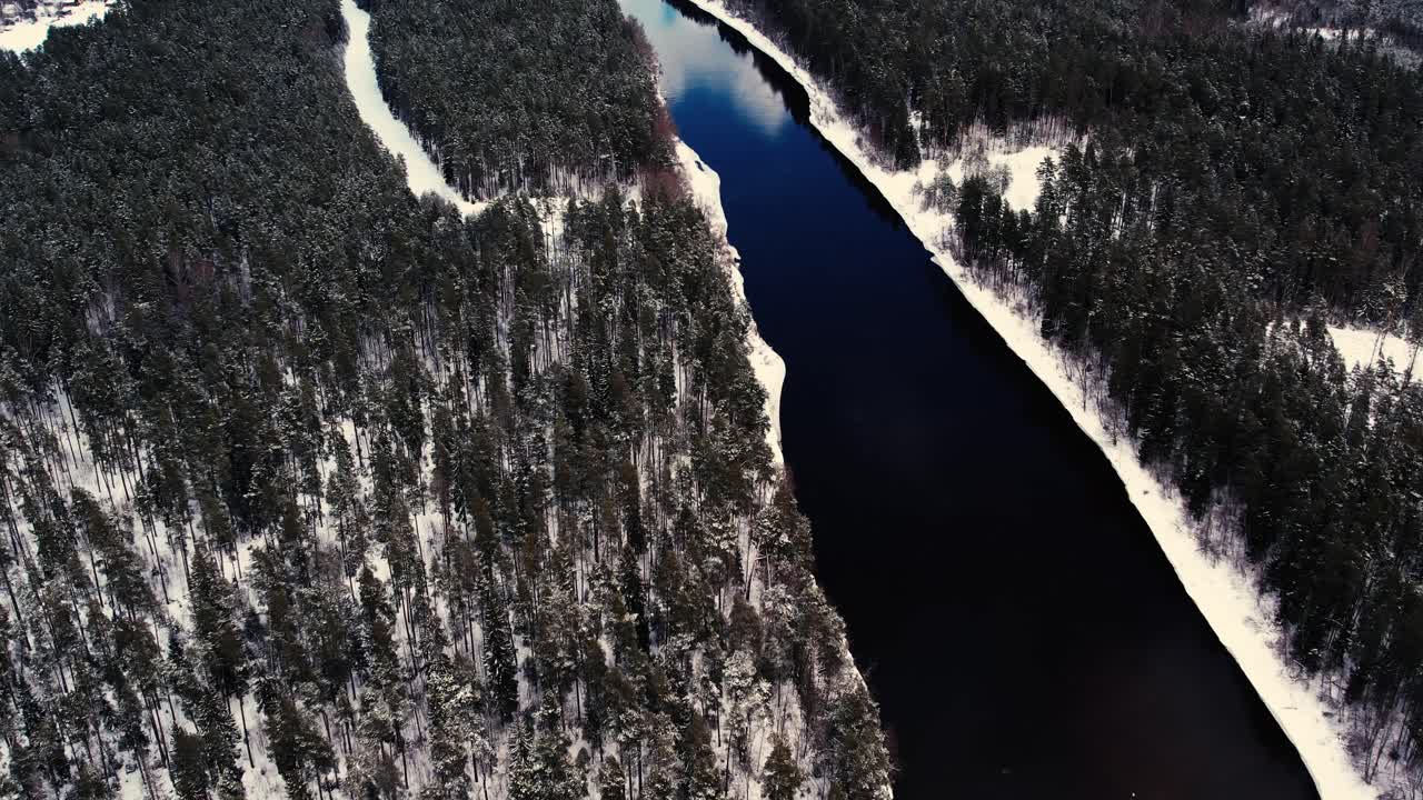 un río sinuoso cerca de un pequeño pueblo con un macizo forestal