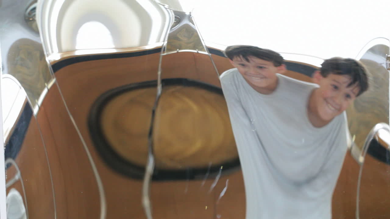 소년은 왜곡 된 거울 앞에서 미소를 짓고 있습니다.