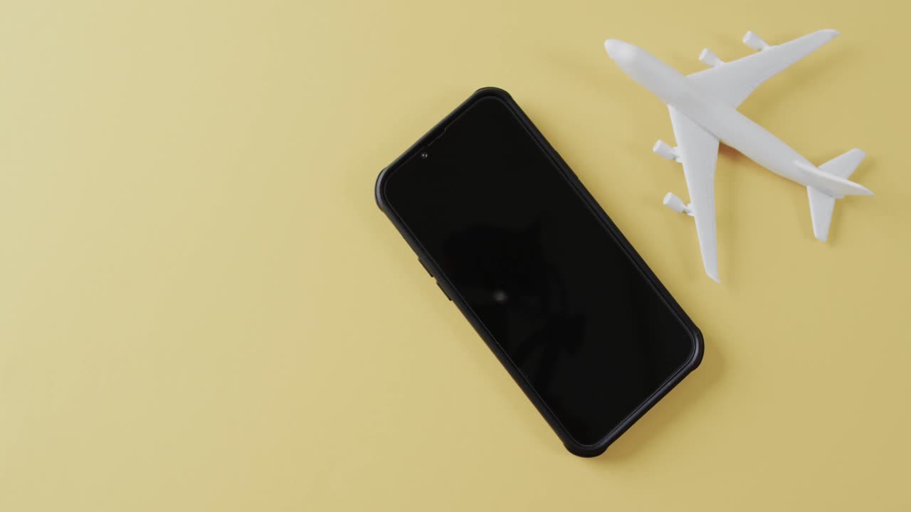 primer plano del modelo de avión blanco, teléfono inteligente y espacio de copia sobre fondo amarillo