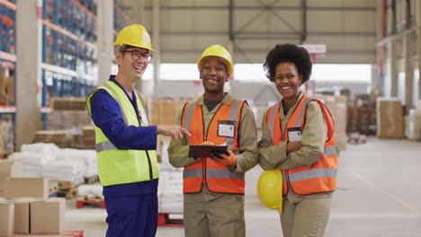 portrait of diverse workers wearing safety suits and smiling in warehouse