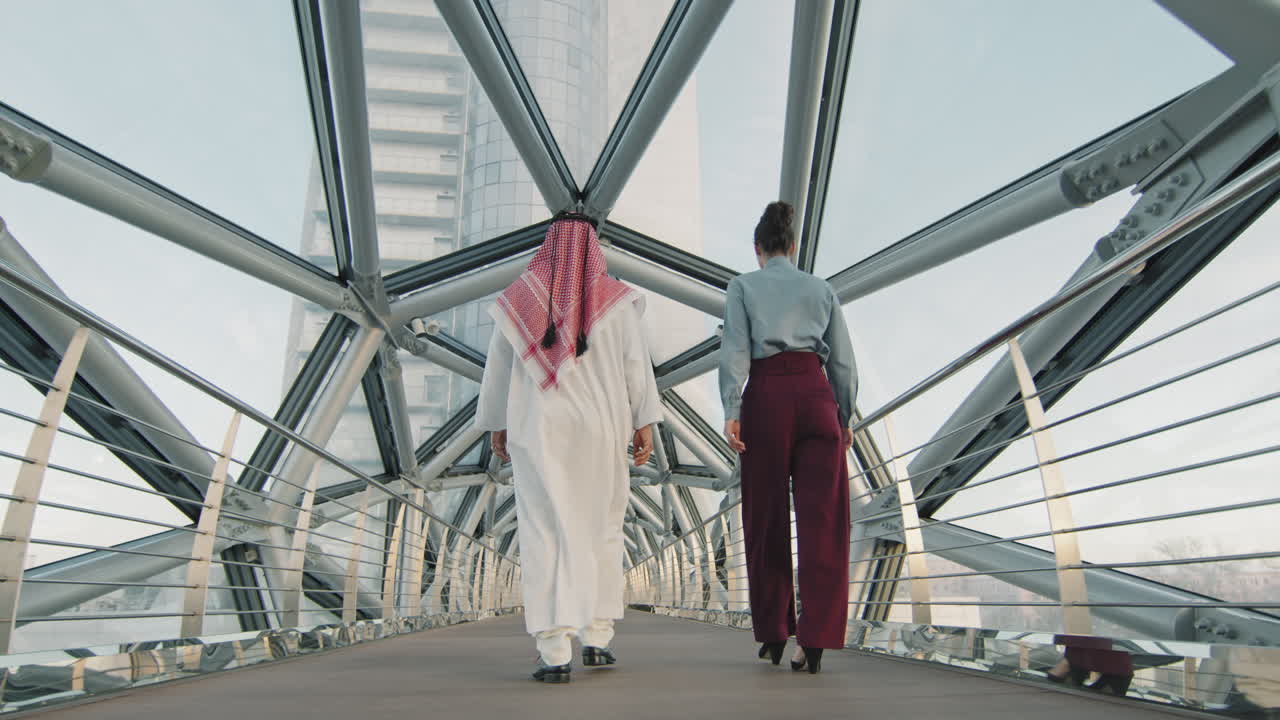 Multi-Ethnic Business Couple Walking Along Glass Bridge