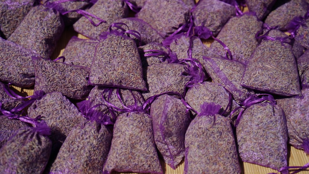 Dried lavender flower buds filling purple mesh sachets, offering a calming scent for relaxation and home fragrance