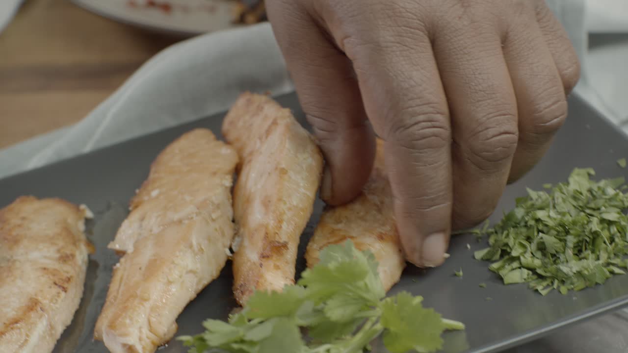 Preparing juicy burger on white board. Chef puts slices of pickled cucumbers on burger bun. Cooking delicious hamburger. Top view