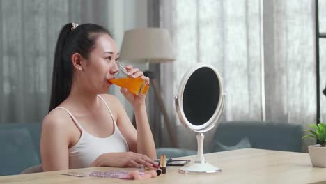 오렌지 주스를 마시고 메이크업을 하는 여자