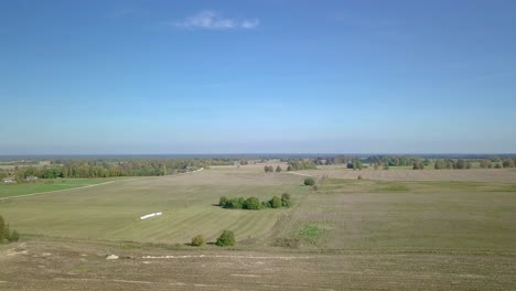 foto aérea ascendente de campos colhidos na zona rural da letônia