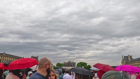 crowd with umbrellas in front of grand architecture