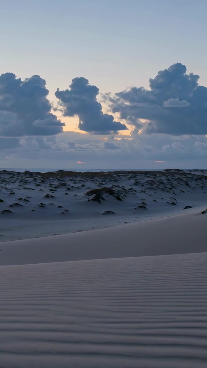 Vertikal video: Lysere kystklitter og lav himmel, mens en solstråle stiger op og viser sandbølger