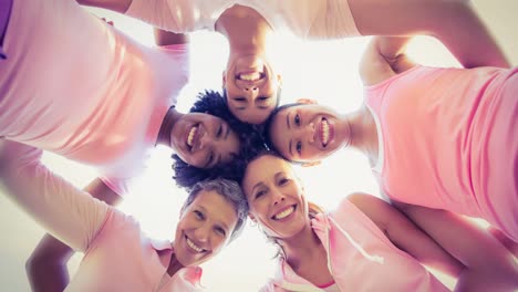 Diverse-group-of-smiling-women-touching-heads-outdoors-in-the-sun