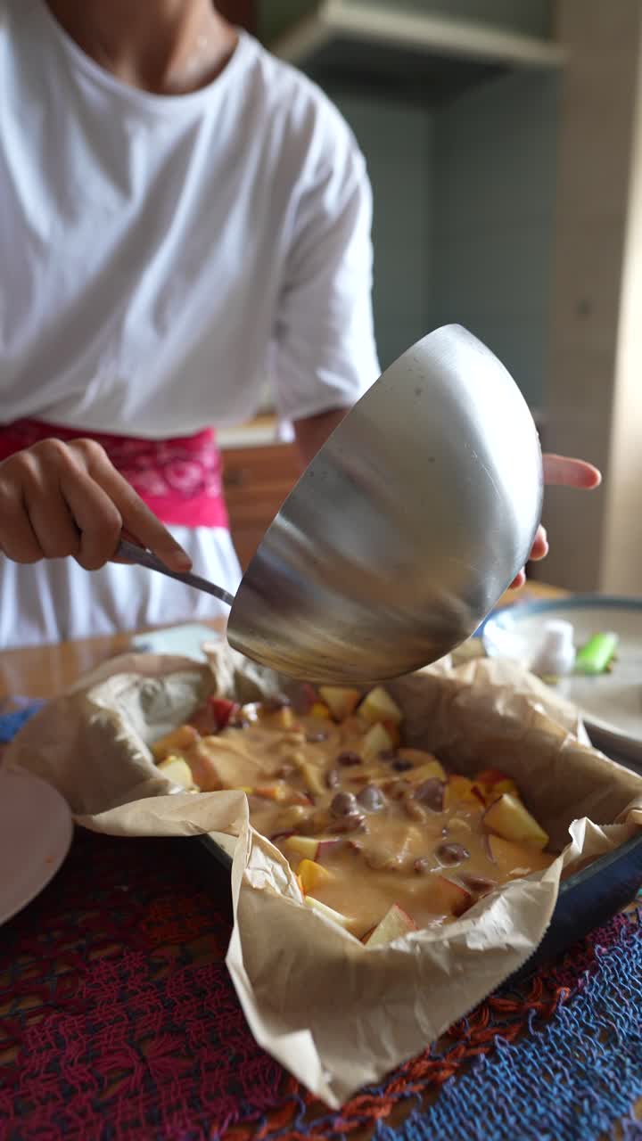 Woman pouring ingredients into apple pie in kitchen