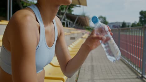 woman resting and hydrating at a stadium after exercise