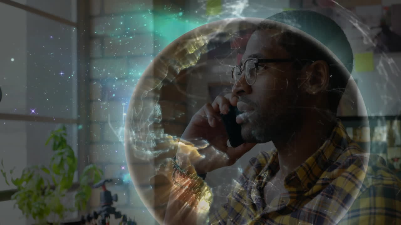 man wearing glasses talking on smartphone in tech office, displaying hologram globe for data