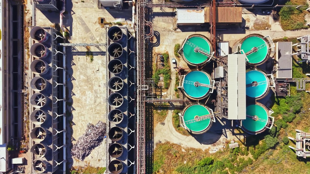 View of water treatment facility with round tanks and pipelines from above in a sunny environment during daylight hours