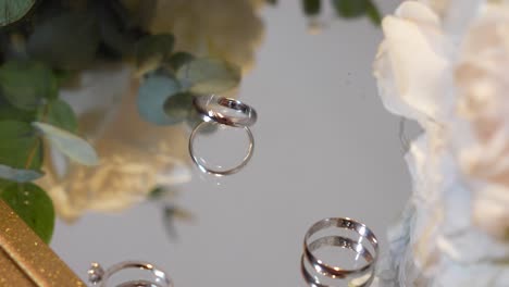 three wedding rings rolling on a glass table