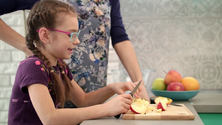 ragazza che mangia una fetta di mela in cucina. bambino che mangia frutta con la madre in cucina
