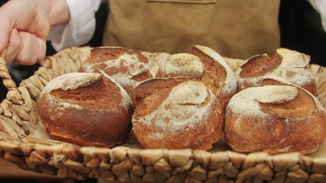 The baker holds in hands a of fresh bread close-up. Artisan bread is making by skill bakers using natural and high-quality ingredients. Food with health and flavour benefits.