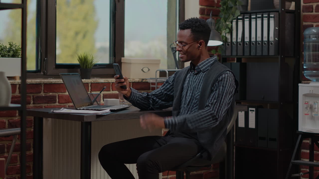 Office worker using smartphone to talk on video call at job
