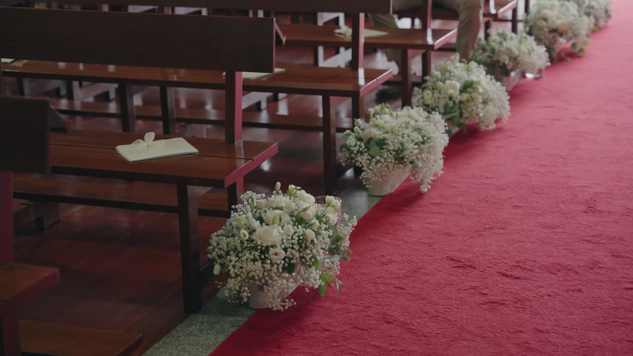 Navata per cerimonia nuziale fiancheggiata da fiori e panche in legno