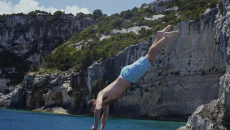 Young-man-dives-into-beautiful-blue-water-on-Greek-island-coastline