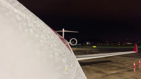 upper fuselage and left wing view after a rainshower of a modern jet in the parking at the airport while other traffic is taking of at the back