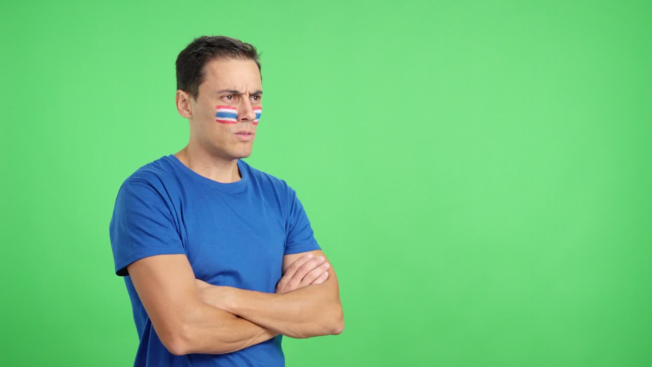 Hombre con la bandera tailandesa pintada mirando hacia otro lado con expresión seria
