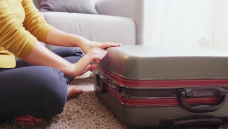 detail of female hands closing suitcase with clothes