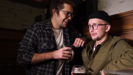 two men talking and drinking beer in a pub