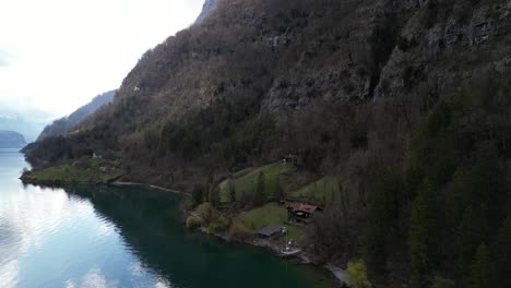 Panning-drone-clip-showing-remote-lakeside-wooden-hut,-perfect-for-a-hiking-vacation,-in-Swiss-alpine-mountains