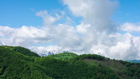 time lapse of white clouds moving over snow covered mountain peaks in the background