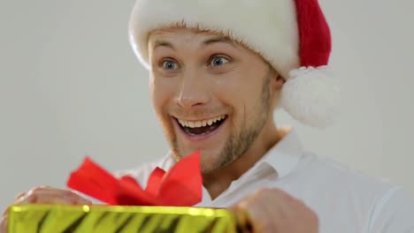 man in santa hat excitedly opens christmas gift