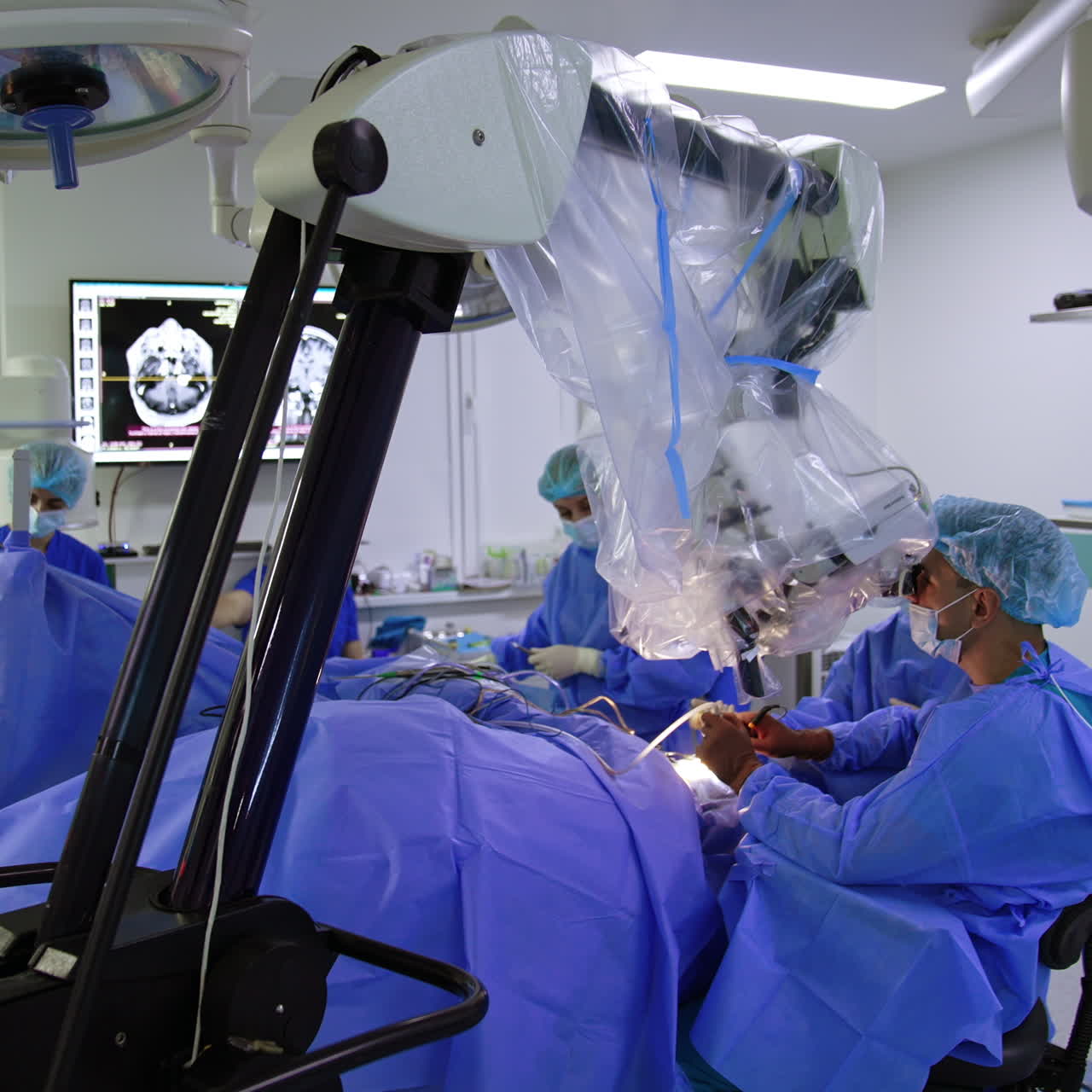 Modern neurosurgical procedure in hospital. Male doctor sits at the patient looking at microscope and applying tools.